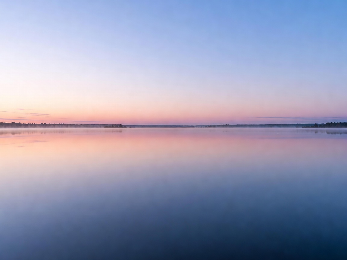 Calm lake water reflecting the sky at dawn